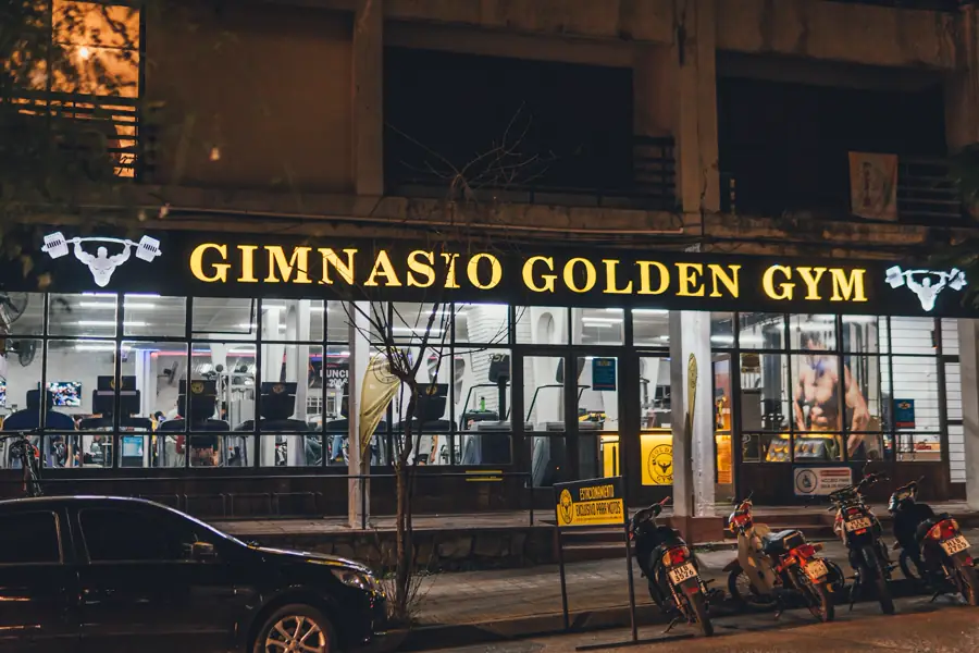 Fachada de Golden Gym Centro de noche, con el cartel dorado encendido